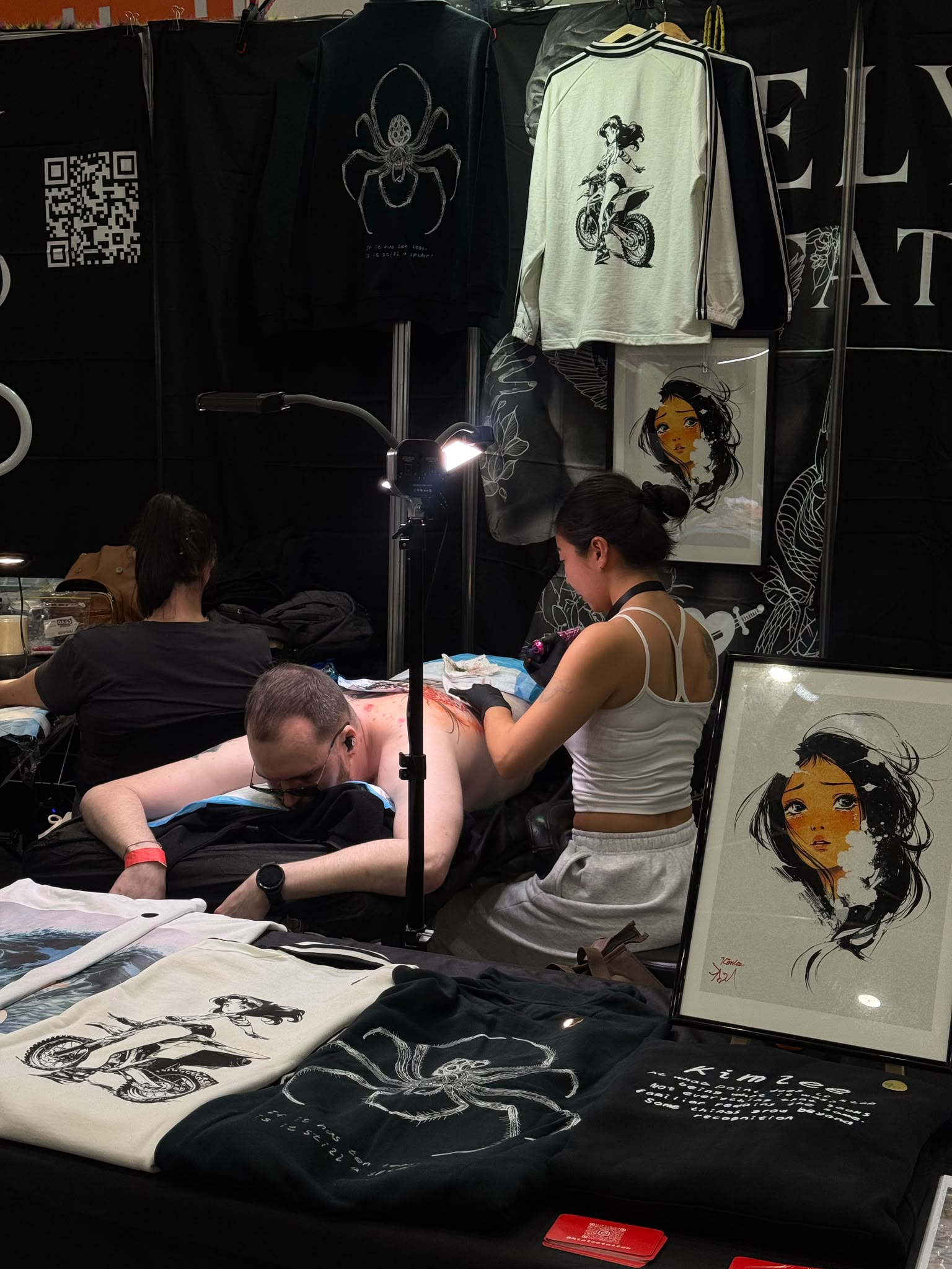 Kim tattooing with her clothing and artwork on display